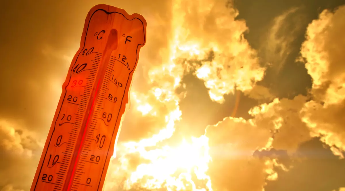 Imaginea prezintă un termometru din lemn profilat pe fundalul unui cer cald, portocaliu și strălucitor, indicând o temperatură ridicată de aproape 40°C.