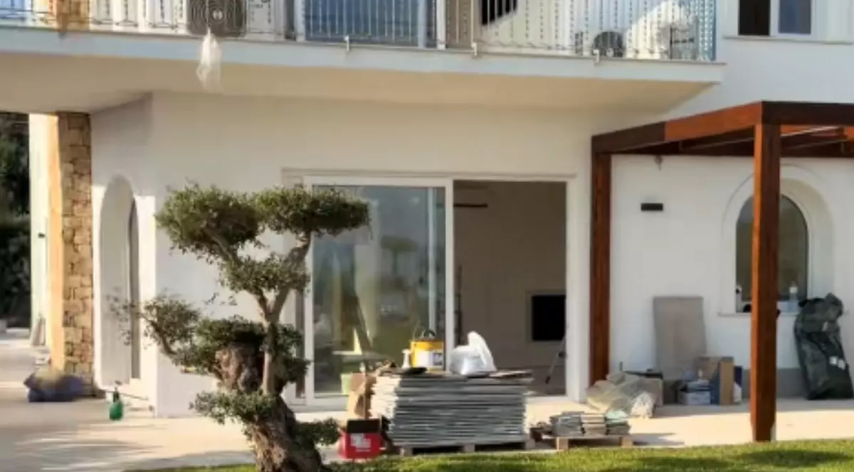 O casă albă lângă care se află materiale de construcție