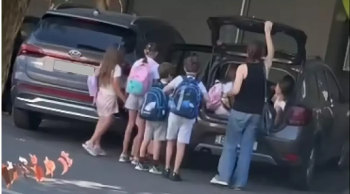 Copii care stau lângă mașini. Unii sunt băgați într-un portbagaj.