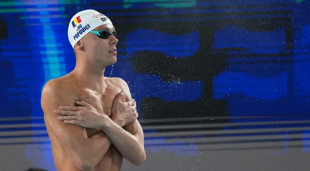 David Popovici, cu ochelari de înot și cască pe cap, lângă bazinul de concurs la Campionatele Europene de Natație 2026 din Paris, cu fundal albastru și negru