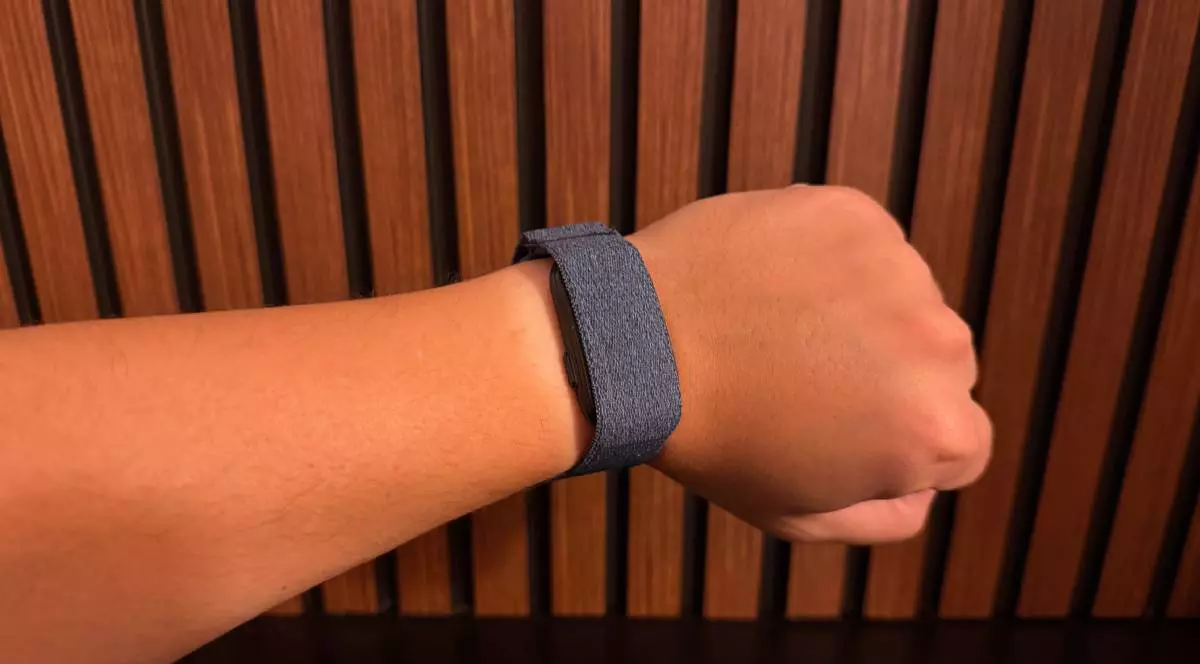 Garmin Cirqa, la încheietura unei mâini, în fața unui fundal de lemn.