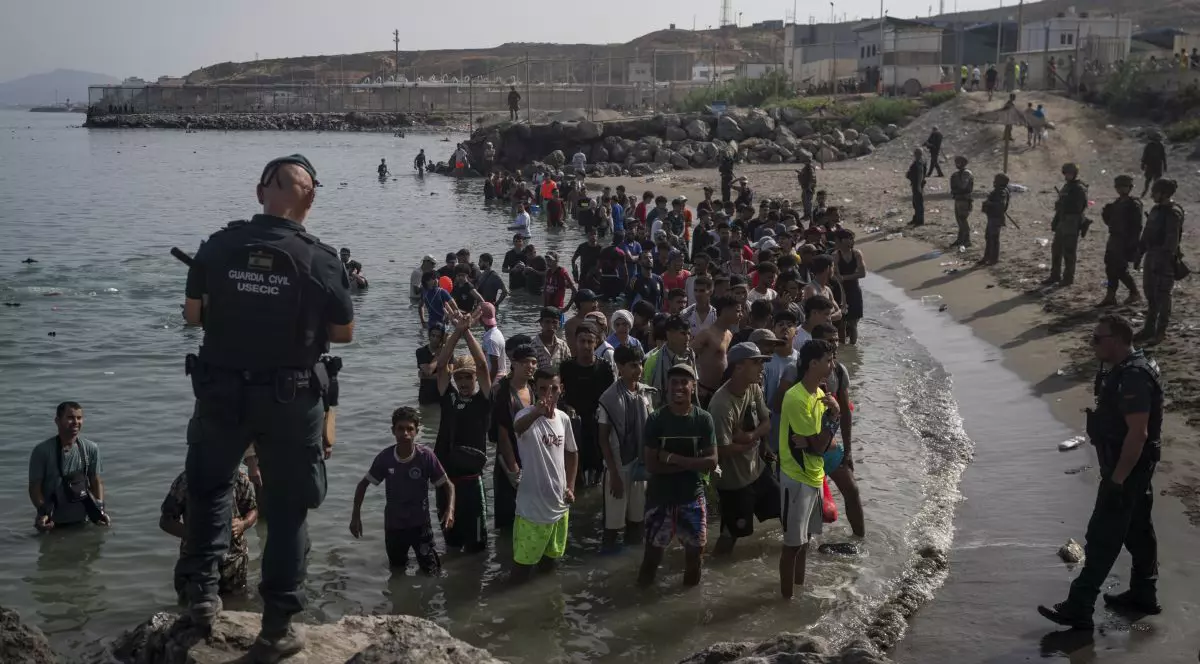 Membri ai unității USECIC din cadrul Gărzii Civile (Guardia Civil) supraveghează migranți pe plaja Tarajal, după ce aceștia au trecut frontiera dintre Spania și Maroc, la 31 iulie 2026, în Ceuta, Spania