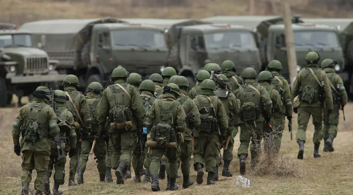 Un grup de militri ruși se îndreaptă către mai multe camioane parcate în apropiere, 2 martie 2014