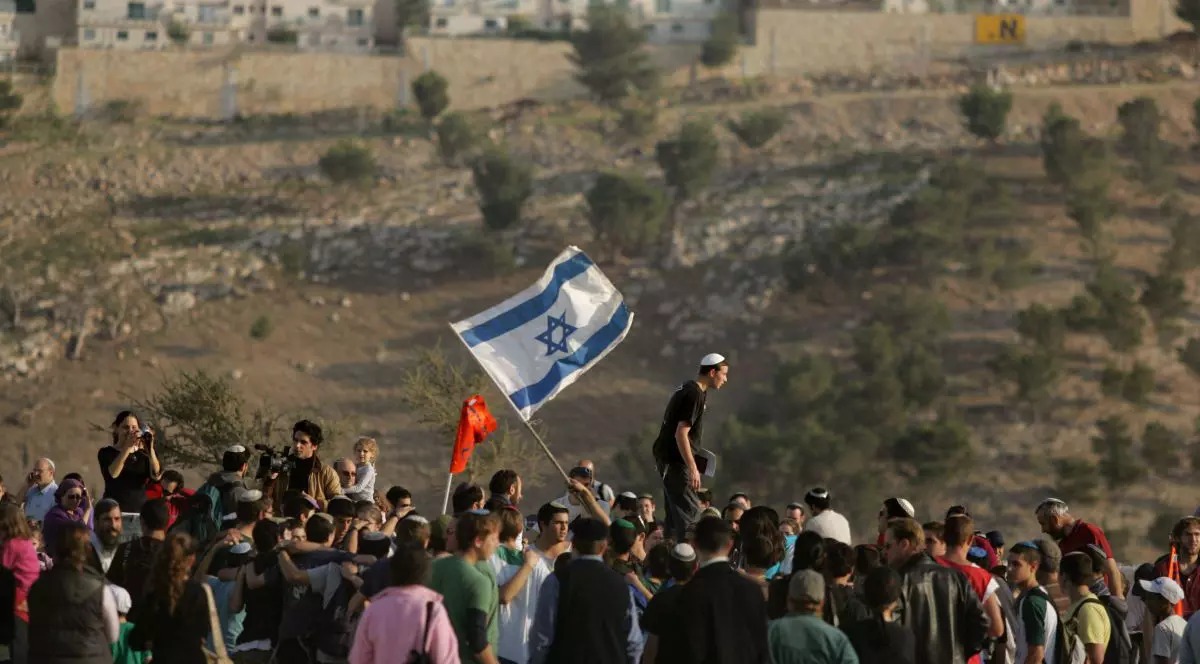 Coloniști israelieni dansează și cântă în timp ce ajung pe dealurile din noua zonă de colonizare E1, la 9 decembrie 2007, în apropierea așezării israeliene Maale Adumim din Cisiordania