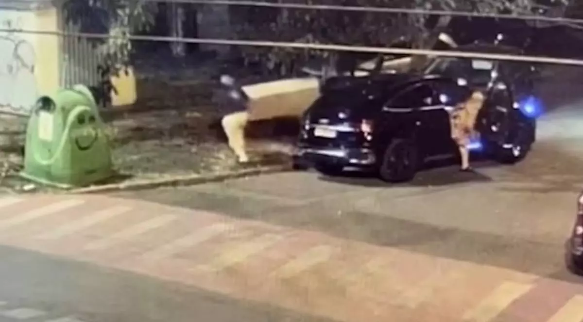 Captură video camere de supraveghere cu un bărbat care este surprins noaptea lângă un Mercedes negru oprit pe o stradă din Timișoara, în timp ce mai multe cutii și obiecte voluminoase sunt lăsate pe trotuar, lângă containerele de gunoi.