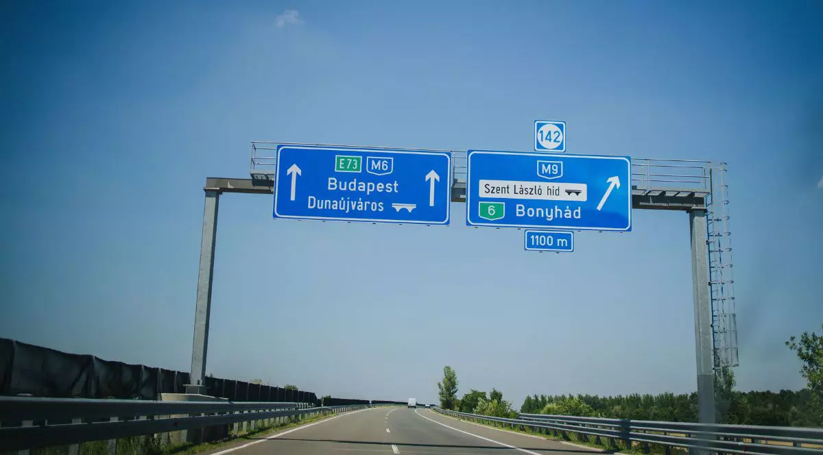 Indicator rutier albastru care indică direcția spre Budapesta, amplasat pe un drum asfaltat, Ungaria – fotografie de stoc
