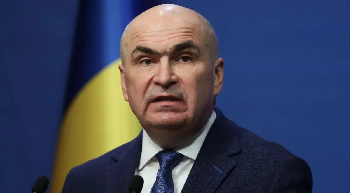 Premierul interimar Ilie Bolojan, cu steagul României în spate, la Guvern, 6 mai 2026
