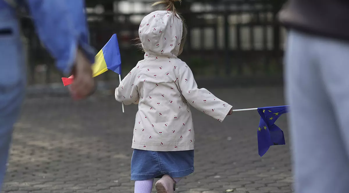 O fetita cu spatele tine in maini un strag al Romaniei si unul al Uniunii Europene