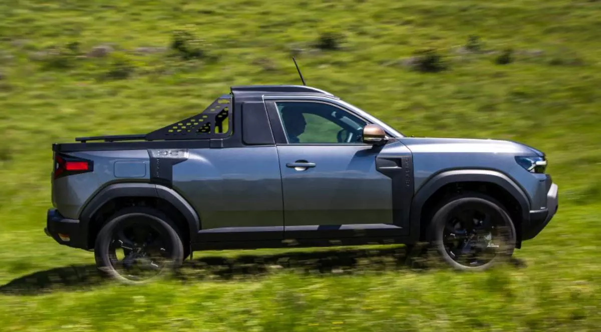 Masina Dacia Duster varianta Pick Up poza din profil pe un camp verde