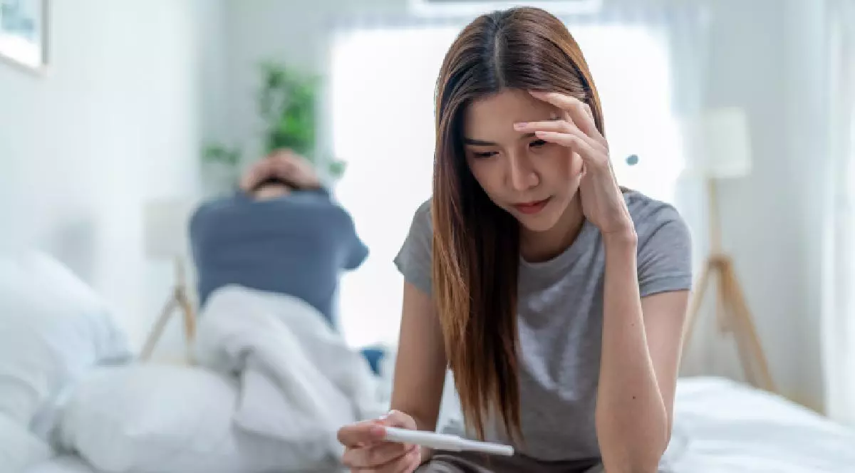 O femeie stă la marginea patului și se uita pe testul de sarcină. Medicii îmi spuneau că e de la stres.Programul national de FIV.
