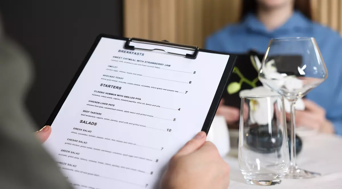 Doi oameni care stau la masă la restaurant și citesc meniul