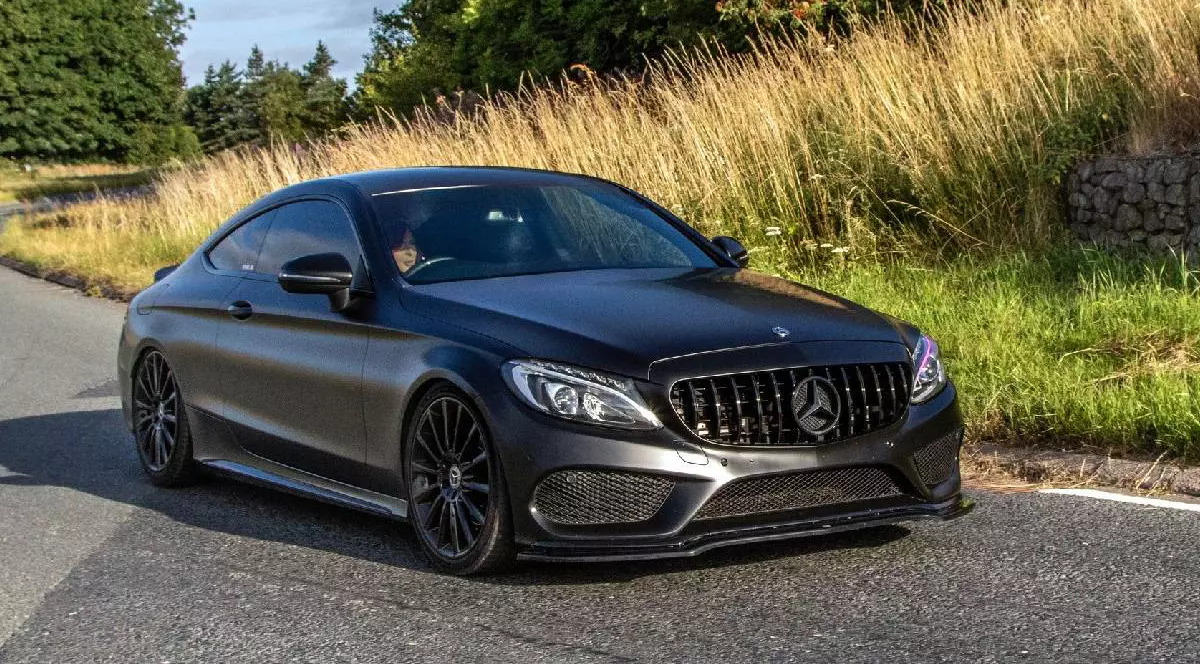 Un Mercedes-AMG C63 rulează pe o șosea mărginită de o câmpie