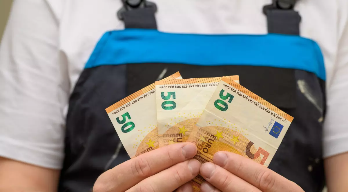 Muncitor în construcții care ține în mâini bancnote de 50 de euro
