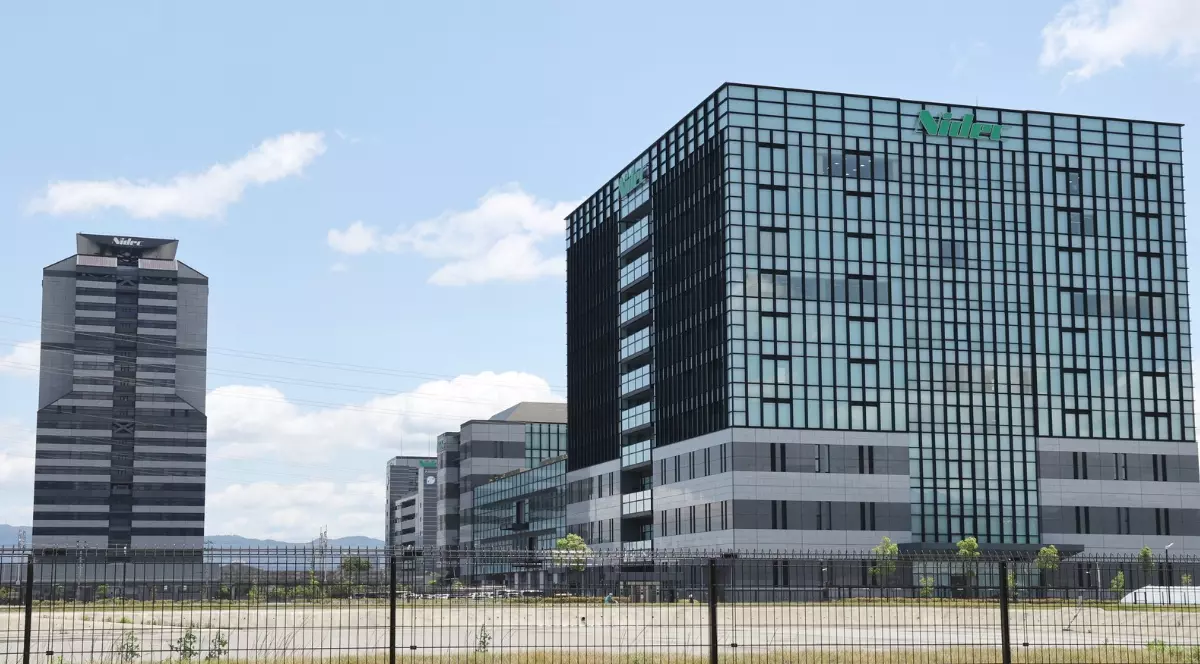 Clădirea sediului Nidec, un complex modern din sticlă, sub un cer senin.