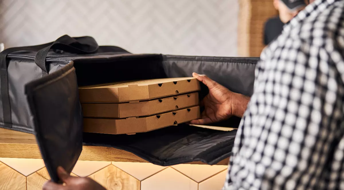 un bărbat care livrează trei pizza