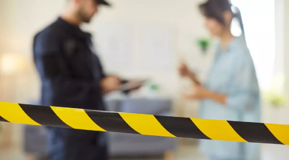 Tânăr polițist bărbat intervievând o femeie după ce a intrat în casă.