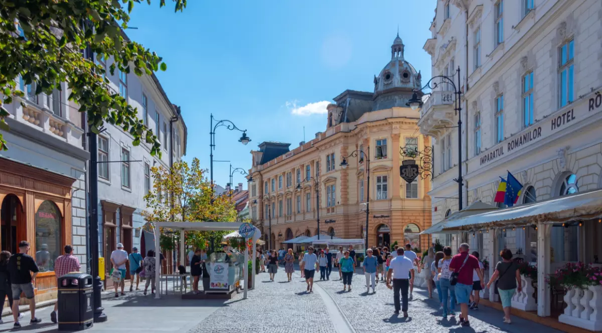 O stradă din centrul orașului Sibiu, oamenii se plimbă pe pietonală în timpul liber