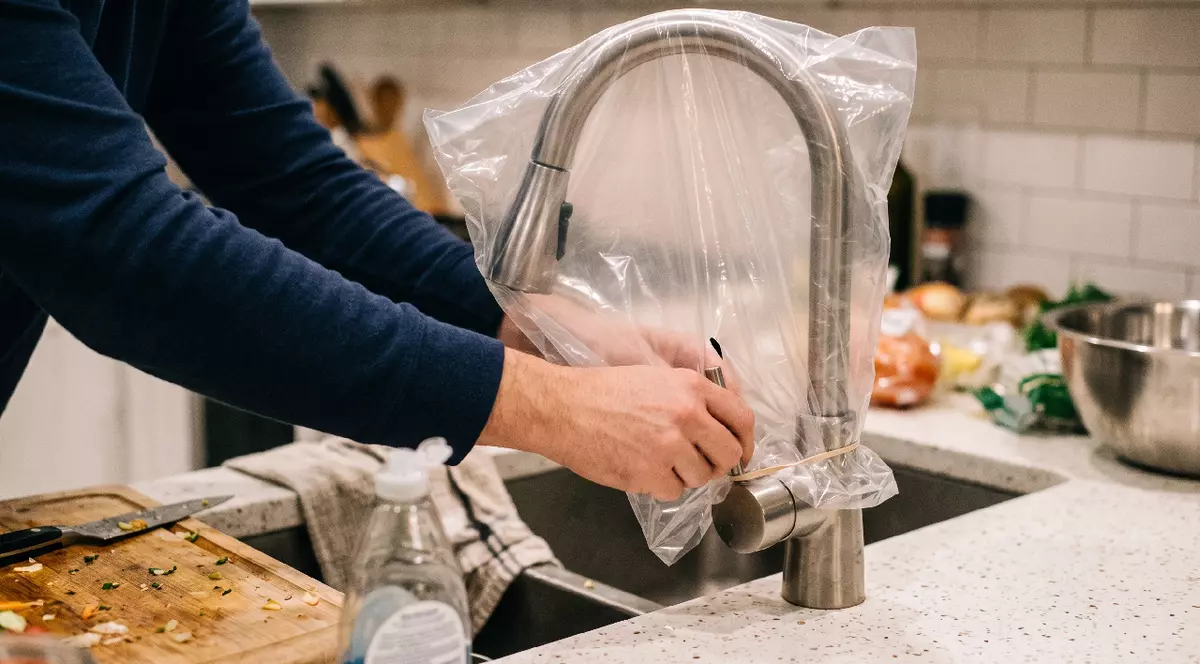 O punga de plastic punsă peste un robinet de inox din bucatarie