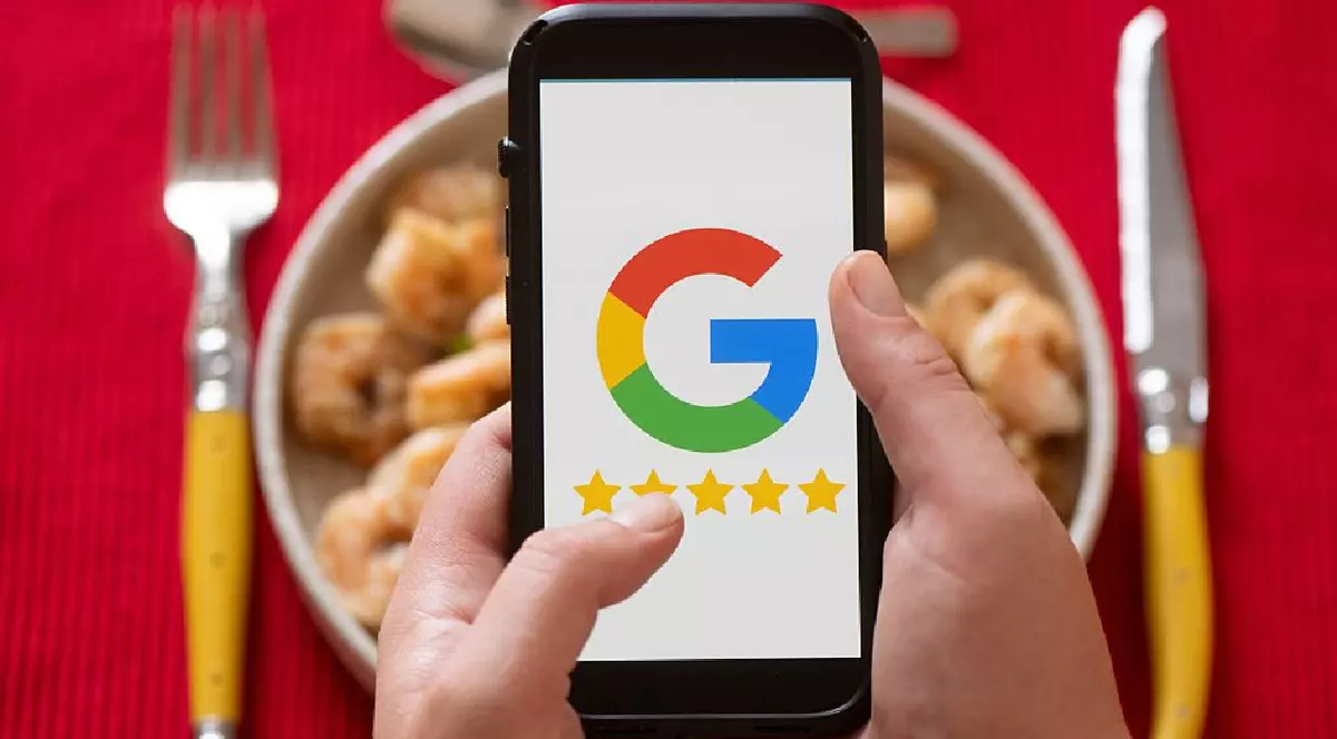 O femeie ține în mână un smartphone cu logo-ul Google în fața unei mese pregătite pentru cină.