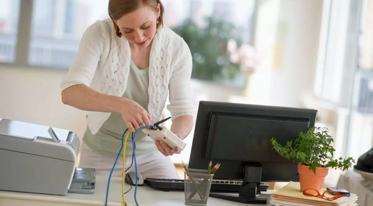 O femeie lucrează la instalarea unui router la biroul de acasă.