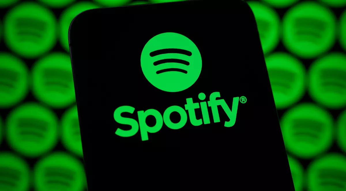 În imagine apare logo-ul Spotify afișat pe ecranul unui dispozitiv mobil, în prim-plan. Fundalul este dominat de mai multe logo-uri Spotify verzi, repetate și estompate.