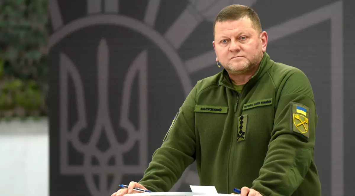 Imaginea îl prezintă pe generalul ucrainean Valeri Zalujnîi îmbrăcat în uniformă militară verde, stând la un pupitru transparent pe un fundal ce afișează stema Ucrainei.