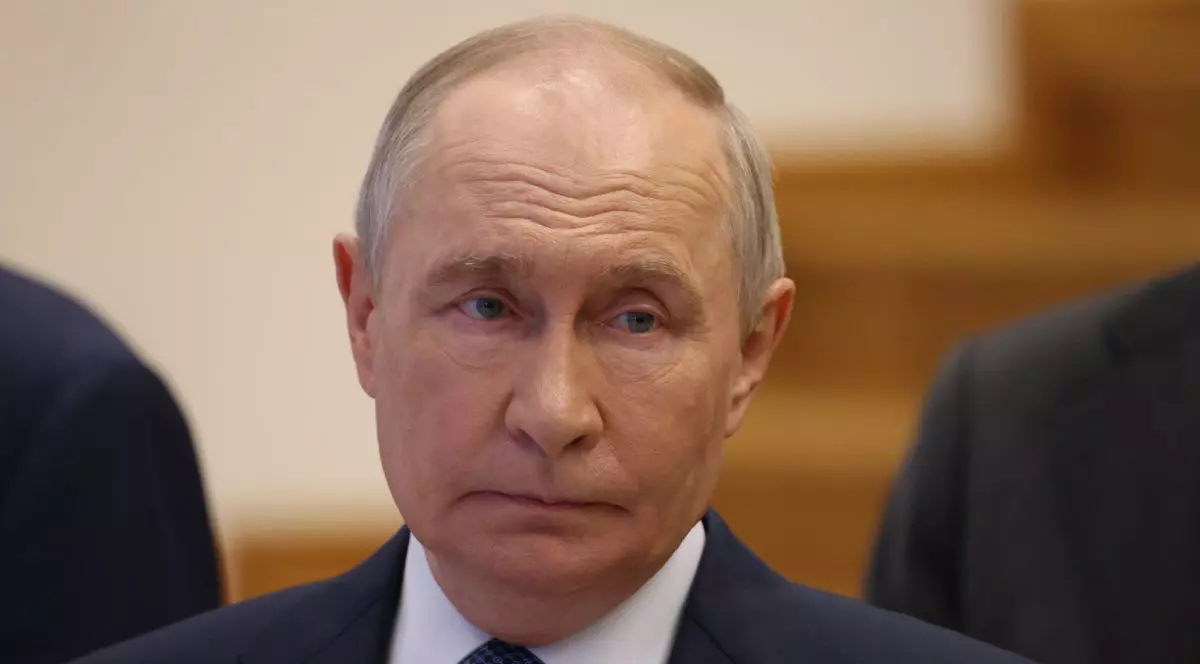 Vladimir Putin, îmbrăcat într-un costum negru, cămașă albă și cravată, cu fundal de culoare maro în blur