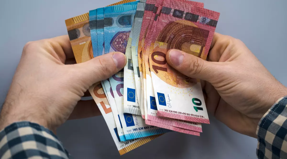 Un bărbat care ține mai multe bancnote de euro în mâini