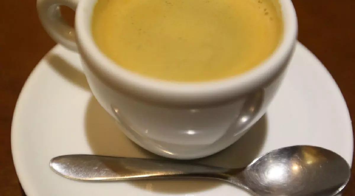 cească de cafea plină, pe o farfurioară, pe care se află și o linguriță