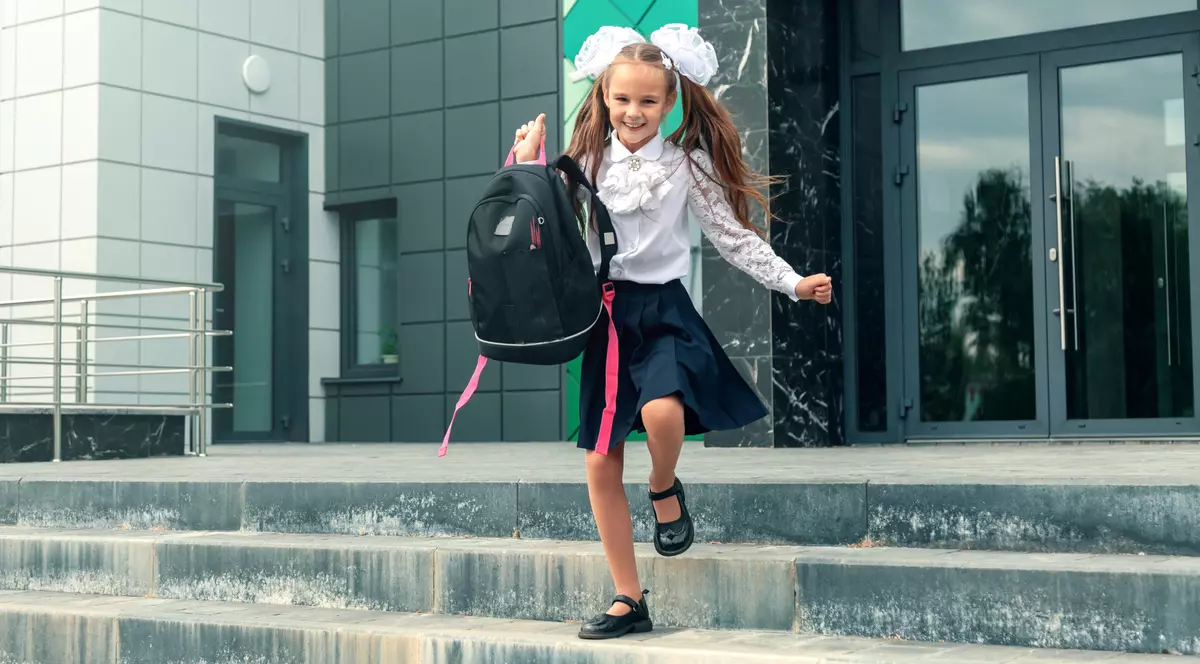 eleva care alearga cu ghiozdanul in brate la inceput de an scolar