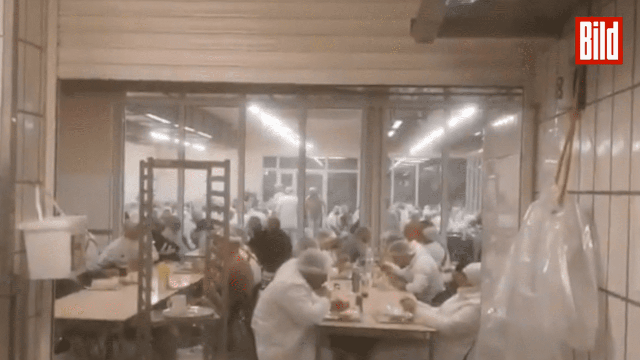 Muncitori servind masa în cantina abatorului Tönnies din Germania. FOTO: captură Bild
