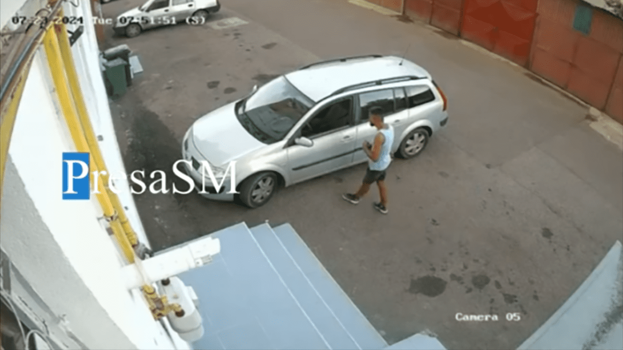 Un bărbat în tricou este suprins pe camerele de supraveghere când se uită la mașina pe care a furat-o ulterior din fața restaurantului