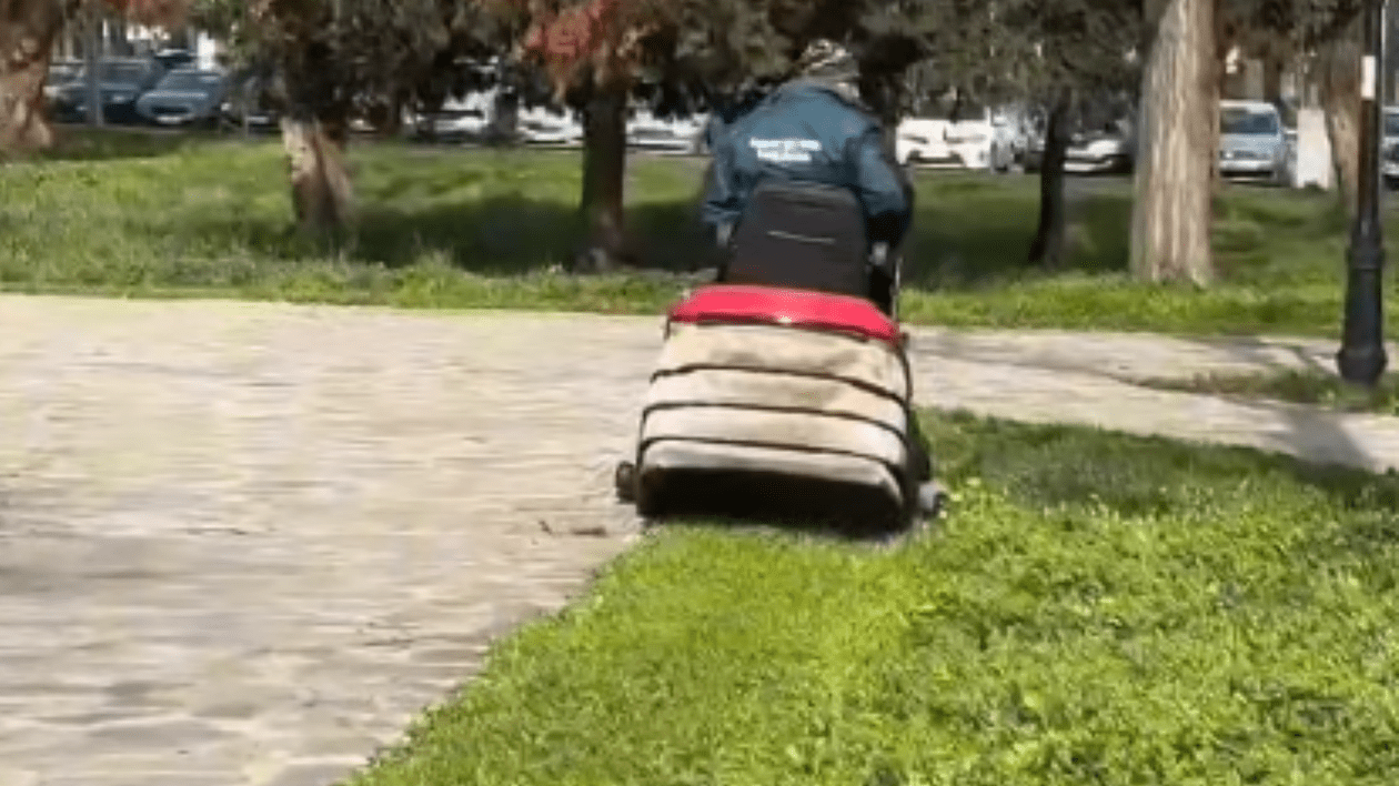 Persoană care tunde iarba cu ajutorul unui utilaj