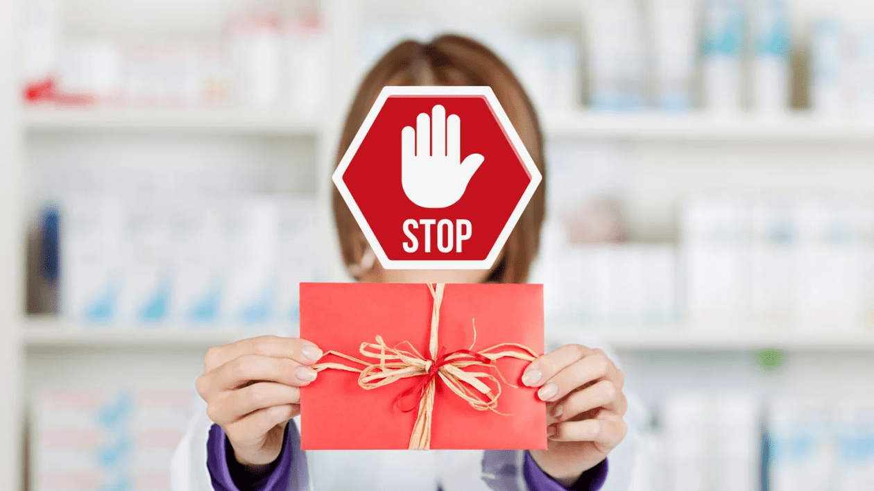 O farmacistă are faața acoperită cu un indicator roșu pe care scrie STOP.