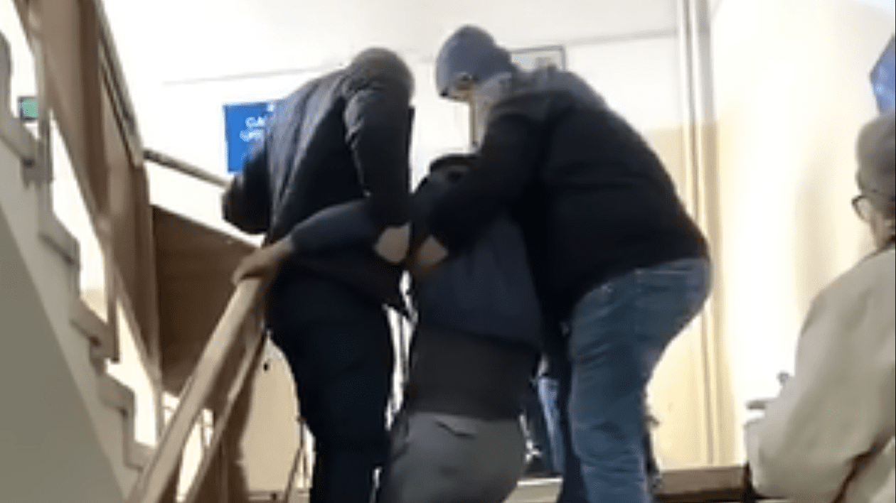 Poză cu pacientul în timp ce este târât pe scări de doi oameni