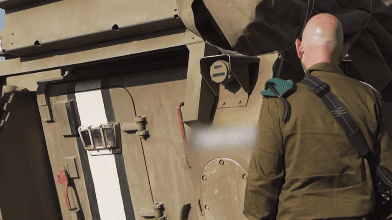 Un soldat israelian stă cu spatele la cameră și privește către un zid.