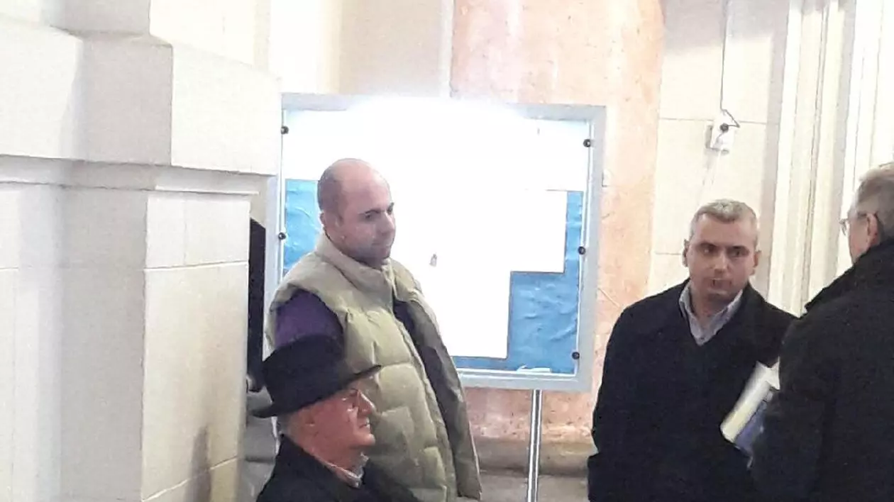 Dumitru Dragomir stă pe o bancă pe holurile Curții de Apel București, în așteptarea începerii unui nou termen în dosarul dezafilierii Universității Craiova. (FOTO: Daniel Conțescu)