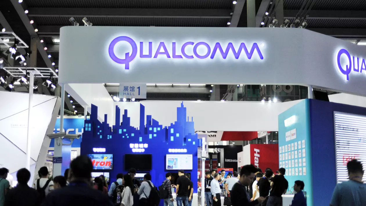 Producătorul de semiconductori Broadcom vrea să cumpere rivalul Qualcomm cu 121 de miliarde de dolari care ar crea un adevărat colos. Noua entitate ar urma să producă mai multe cipuri din smartphone-urile vândute pe plan mondial, de la procesoarele centrale la modemurile care fac legătura cu rețelele telecom la cipurile Wi-Fi și Bluetooh. Stand Qualcomm cu oameni care îl vizitează și logo-ul companiei deasupra