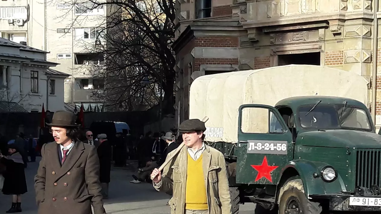 Imagini de la filmările pentru Moromeții 2 din centrul Capitalei. Doi figuranți stau în fața unui camion rusesc, cu celebra stea roșie pe ușă