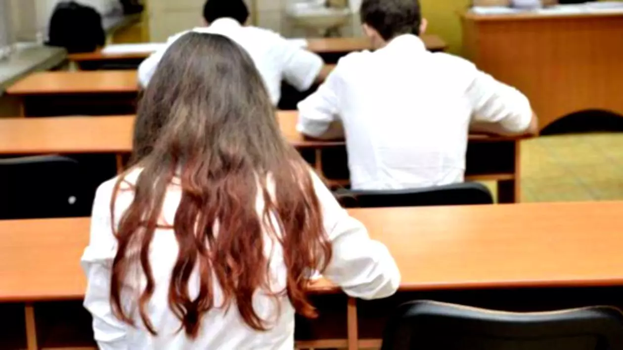 Studenţii de la ASE pot să treacă anul şi cu note mai mici de 5. Studenți, în bănci, la un examen. Sunt fotografiați cu spatele