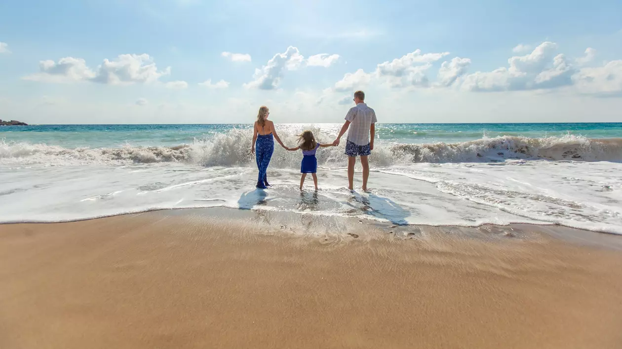 destinații ieftine în Europa, pentru o săptămână la plajă, în 2018. Doi părinții cu o fetiță, care intră în valurile mării