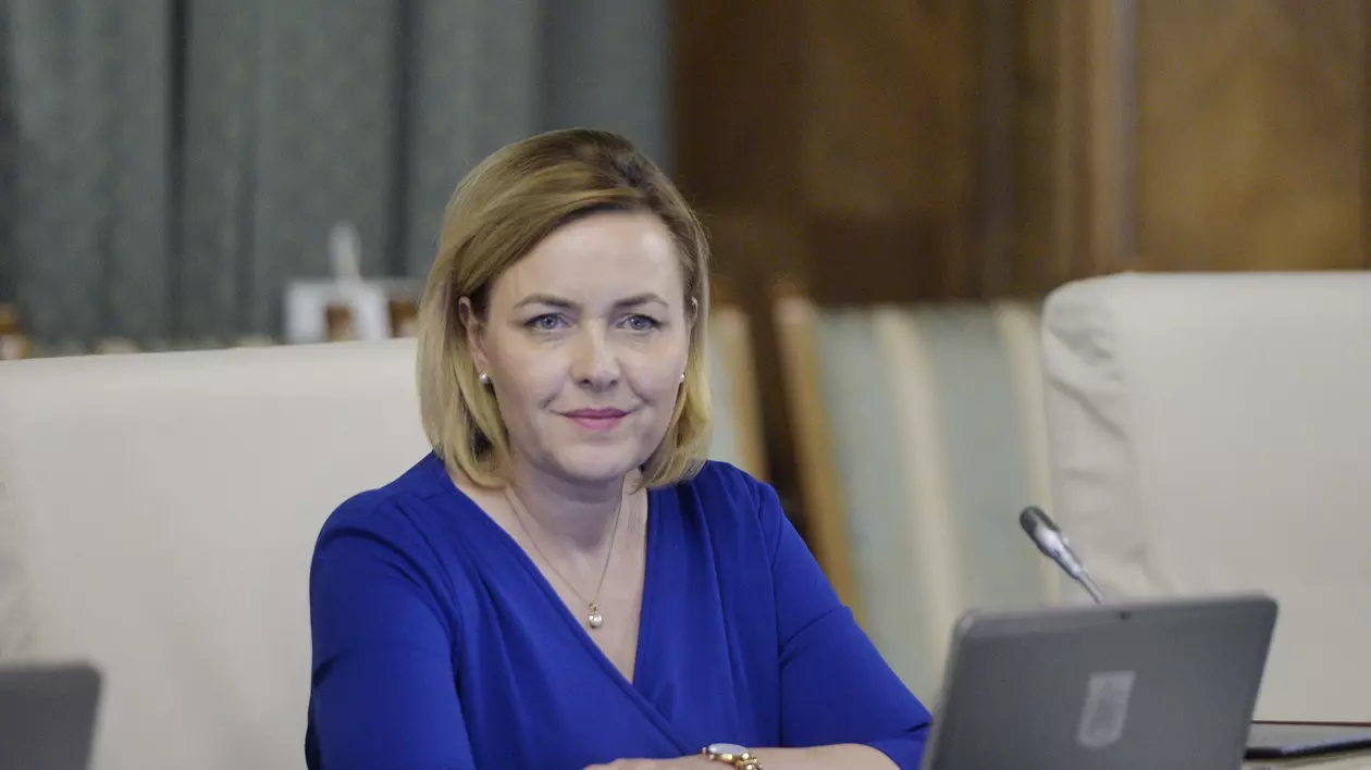Măsurile luate de MAI pentru mitingul de la Ateneu. Ministrul de Interne, Carmen Dan, zâmbind, îmbrăcată în albastru, cu mâinile, una peste alta, pe birou