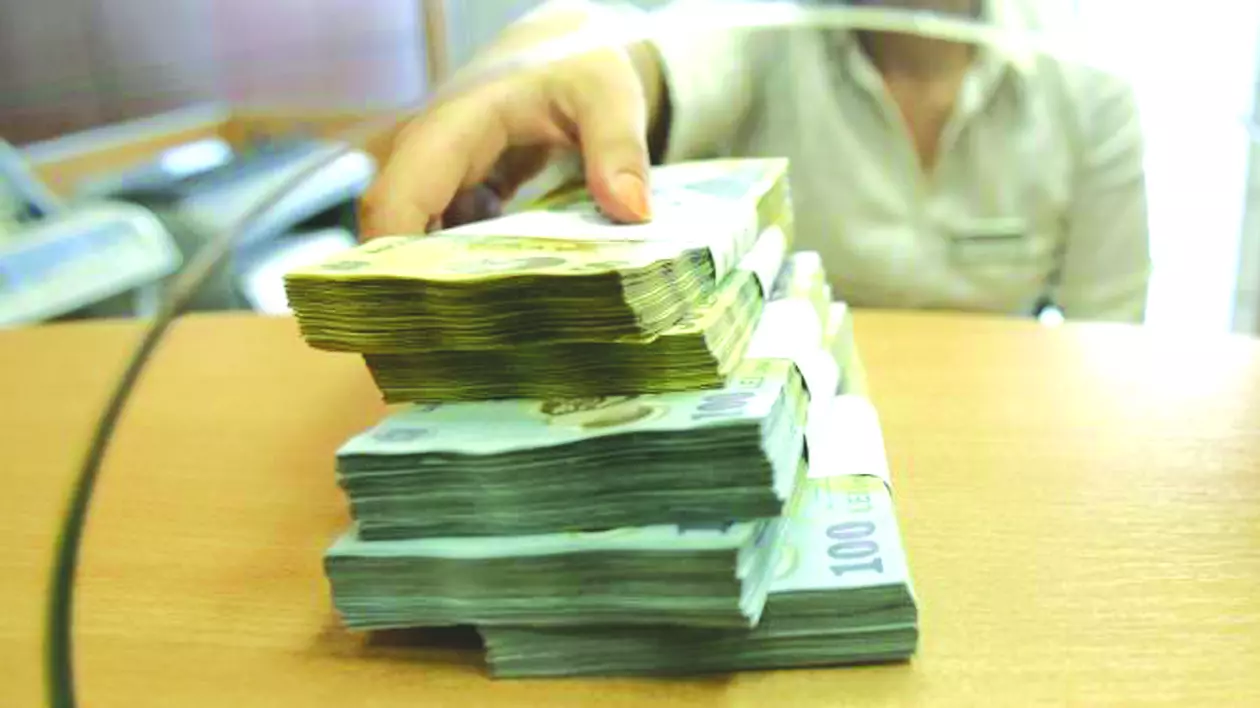 Amânarea ratelor vine la pachet cu raportarea la Biroul de Credit. Băncile spun că nu e motiv de îngrijorare. Teancuri de bani la un ghișeu bancar