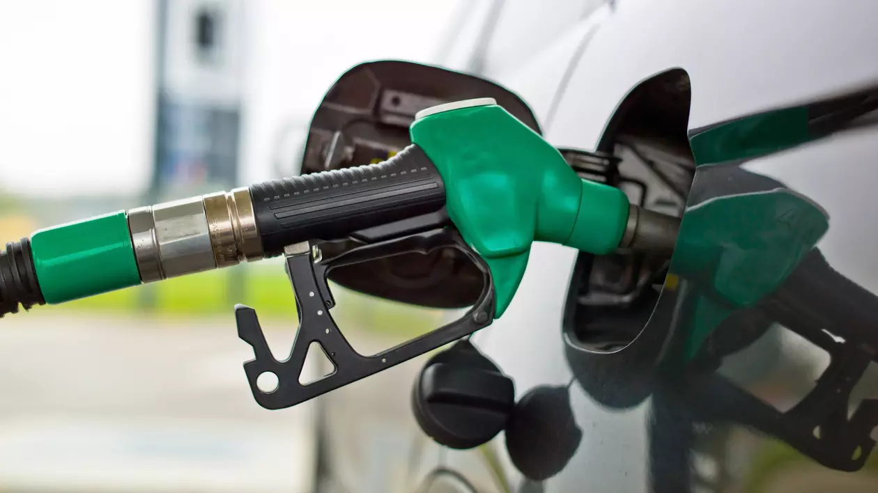 O pompă verde alimentează un automobil de culoare neagră.