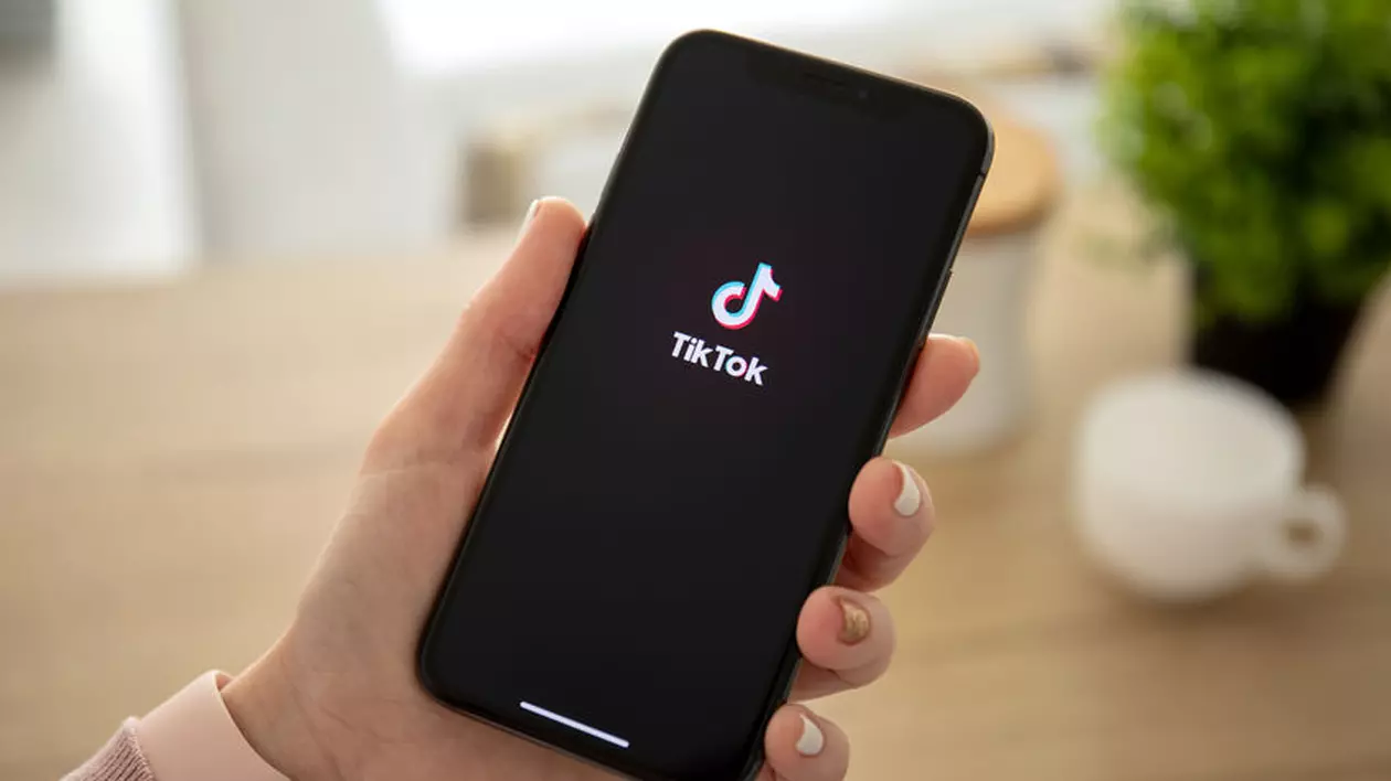 O femeie ține în mână un telefin pe care asteapta sa se deschida aplicatia TikTok