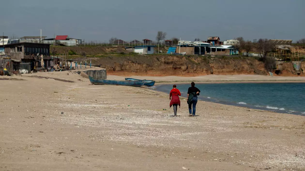 Cum vor fi concediile în acest an? Hotelurile vor lua temperatura angajaților, se deschid mai întâi terasele, fără all-inclusive, pe plajă se mărește distanța între șezlonguri. Doi oameni mergând pe o plajă