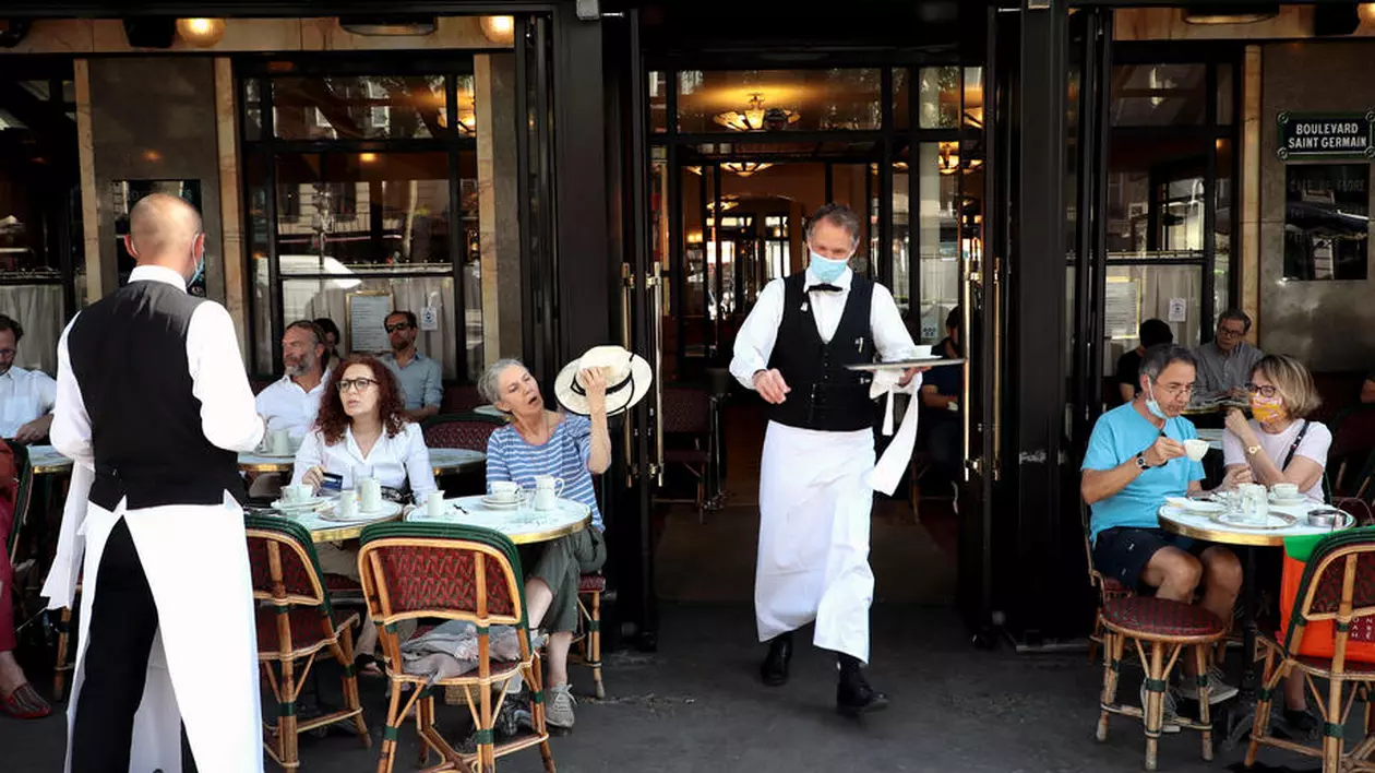 Firmele își pot amâna taxele până pe 25 octombrie, iar restaurantele și turismul au trei luni de scutire la impozitul specific. Chelneri cu mască la o terasă