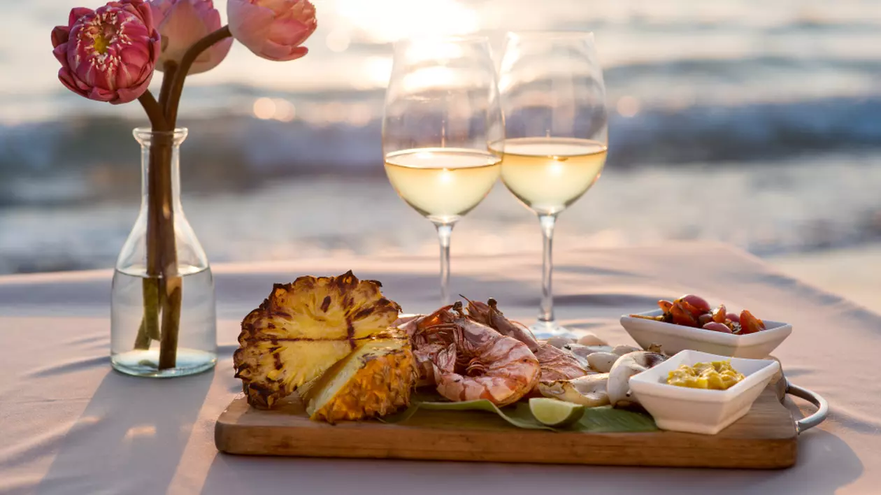 Câte tipuri de vin alb există - Cină romantică la restaurant pe plajă cu vedere la apusul soarelui.
