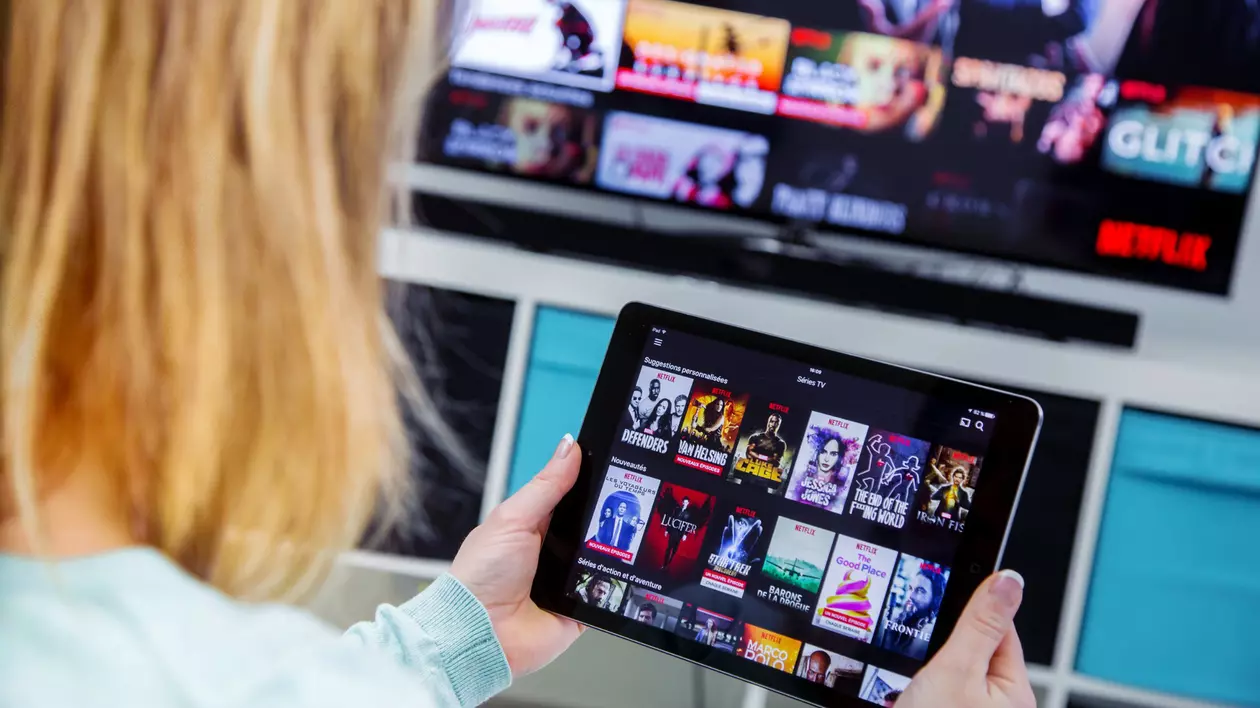 Netflix, HBO Max, Amazon Prime, Disney+. Care serviciu de streaming este mai bun? - O femeie priveşte la o tabletă care afişează pagina de start a unui serviciu de streaming.