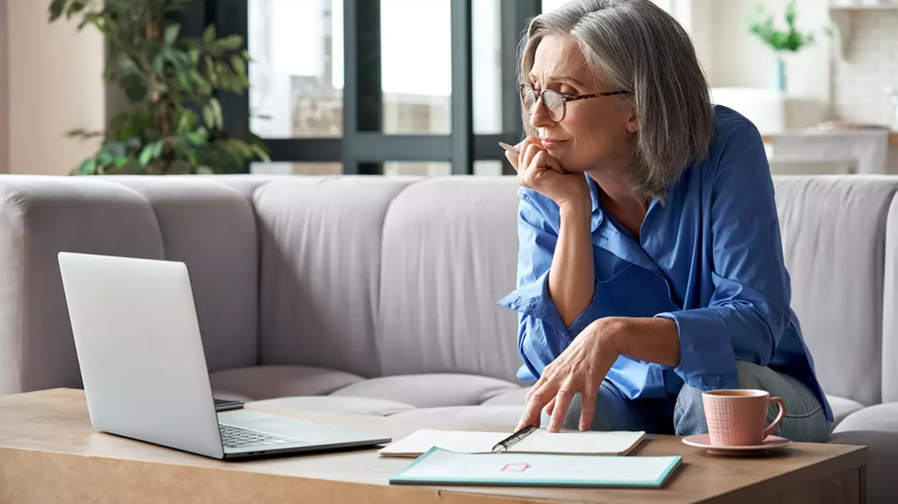 La ce vârstă se pot pensiona femeile - Imagine cu o femeie în vârstă care lucrează cu un laptop